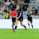 Sally Menti wearing a dark blue uniform jumps in the air and celebrates on a soccer field