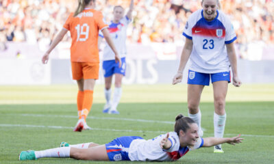 Ella Toone celebrates her goal by lying on the pitch with her arms extended like she is flying.